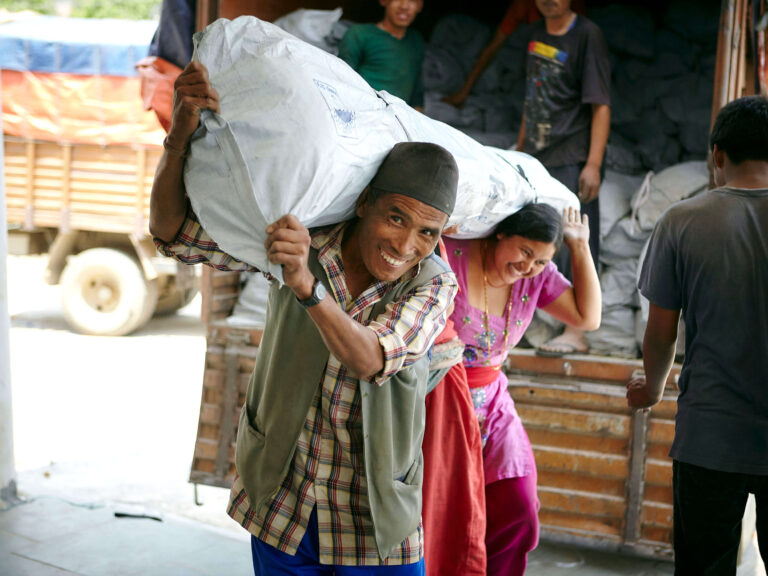 Man and woman carrying shelter kit after earthquake in Nepal