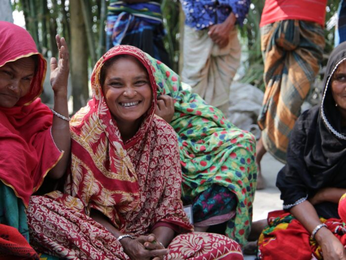 Group of people sitting on the floor smiling in Bangladesh