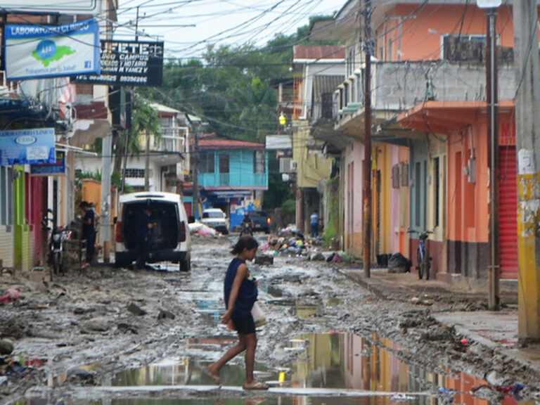 A woman walks on a flooded street in Honduras