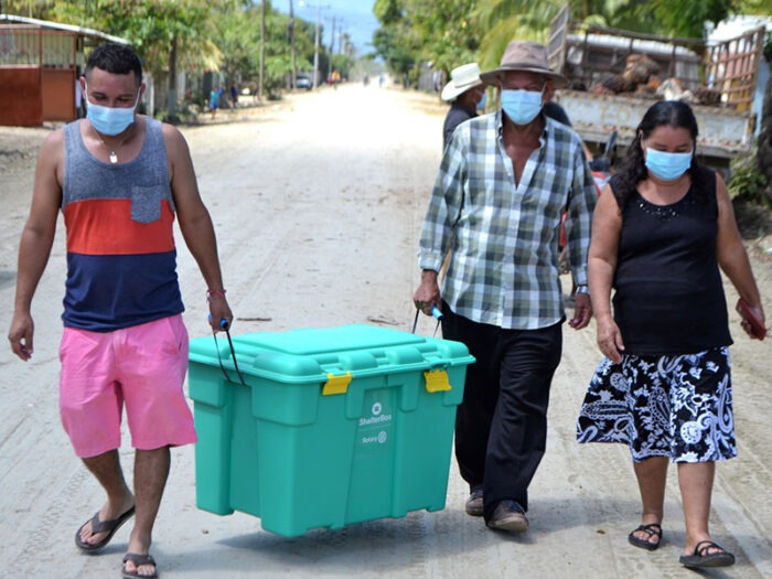 3 people wearinf carrying a green box
