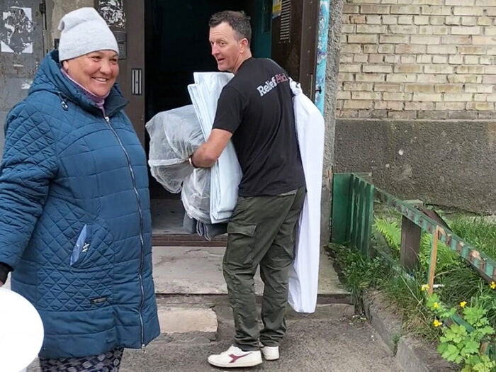 A man carrying aid inside a woman's house.