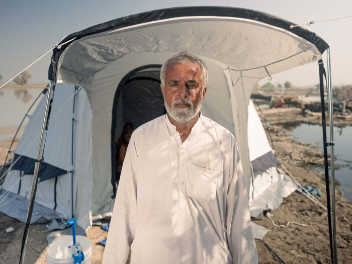 Man stands unsmiling outside emergency relief tent after flooding in Pakistan
