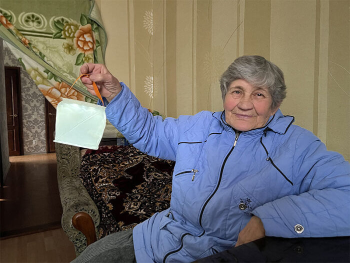 Ukrainian woman in blue winter coat holds up solar light