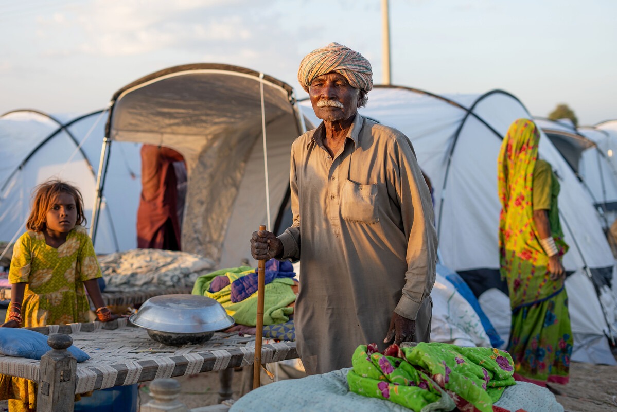 Man in grey and little girl standing next to tables in front of tents