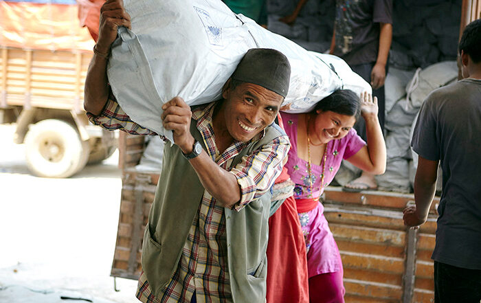 Man and woman carrying a bag of aid in Nepal