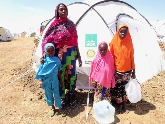 A woman standing in front of a tent with three children around her