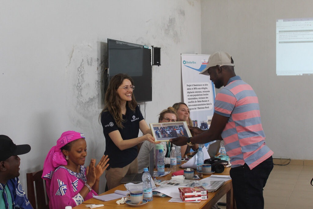 Two people shaking hands as one gives the other a photograph in Cameroon