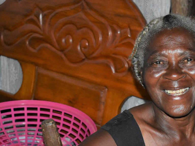 Woman sitting in her home and smiling at the camera in Haiti