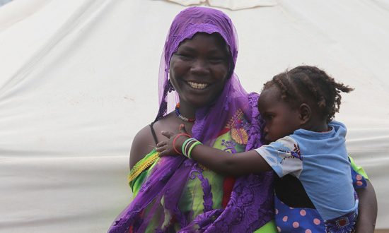 Woman holding a young child in front of a tent in Chad